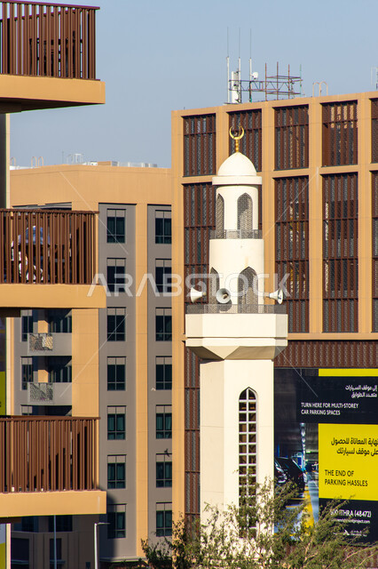 منارة مسجد في مدينة العين بإمارة أبو ظبي بدولة الإمارات العربية المتحدة، العبادة والتقرب الى الله، منظر جمالي لمئنة المسجد خلف الاشجار، اقامة الصلاة، الفن الاسلامي المعماري، صوت الآذان، دعوة المسلمين للصلاة