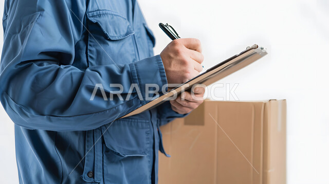 الطلبات الاونلاين والتسوق الذكي, مفهوم التسوق الالكتروني, توصيل الطلبات والبضائع للزبائن, عمليات شحن وتوصيل موثوقه, بورتريه مقرب لرجل عربي خليجي سعودي يرتدي بدلة عمل زرقاء يقوم بتسجيل وكتابة البيانات والملاحظات، خلفية بيضاء