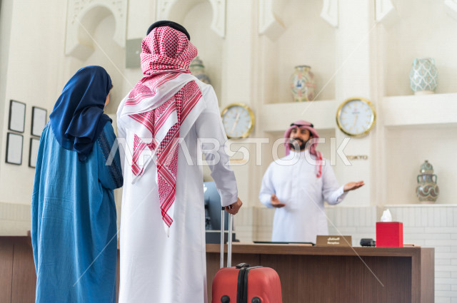 زوجان سعوديان سائحان يقومان بإجراءات الحجز عند مكتب الاستقبال في الفندق , سياحة وفندقة , قضاء أوقات ممتعة , رحلة زوجية سعيدة , سياحة وسفر , خدمة العملاء في الفندق السياحي