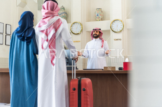 زوجان سعوديان سائحان يقومان بإجراءات الحجز عند مكتب الاستقبال في الفندق , سياحة وفندقة , قضاء أوقات ممتعة , رحلة زوجية سعيدة , سياحة وسفر , خدمة العملاء في الفندق السياحي