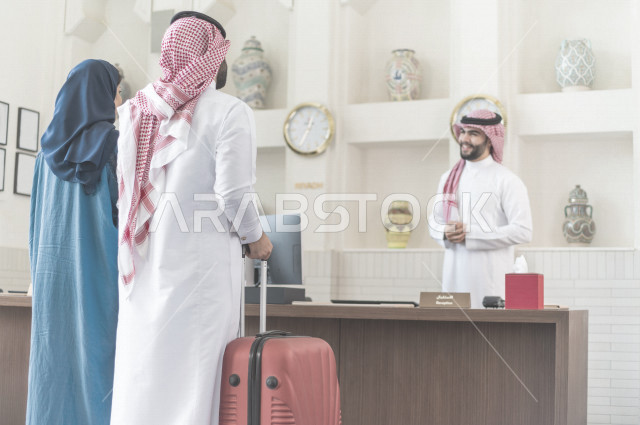 زوجان سعوديان سائحان يقومان بإجراءات الحجز عند مكتب الاستقبال في الفندق , سياحة وفندقة , قضاء أوقات ممتعة , رحلة زوجية سعيدة , سياحة وسفر , خدمة العملاء في الفندق السياحي