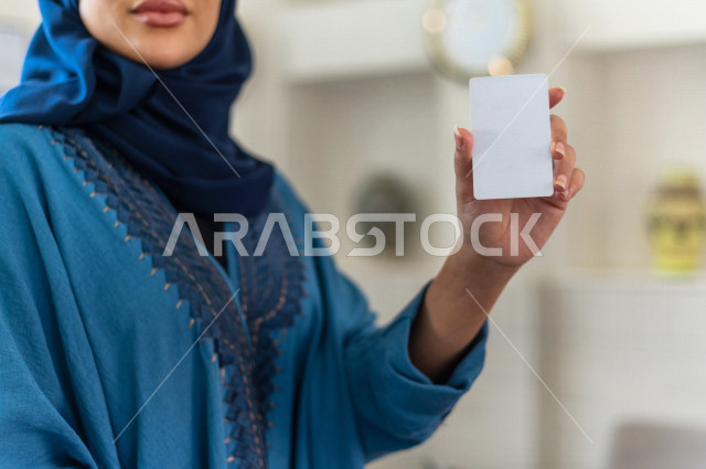 A close-up of a veiled Saudi Gulf receptionist holding a blank identification card with different facial and hands gestures, tourism and hospitality, customer reception desk, travel and tourism, customer service in the tourist hotel