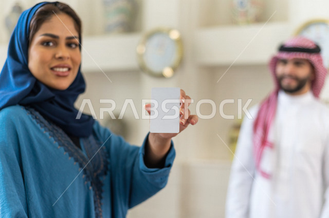 صورة مقربة لموظفة إستقبال خليجية سعودية محجبة تحمل كرت تعريفي فارغ بإيماءات وجه ويدين مختلفة , سياحة وفندقة , مكتب إستقبال العملاء , سياحة وسفر , خدمة العملاء في الفندق السياحي