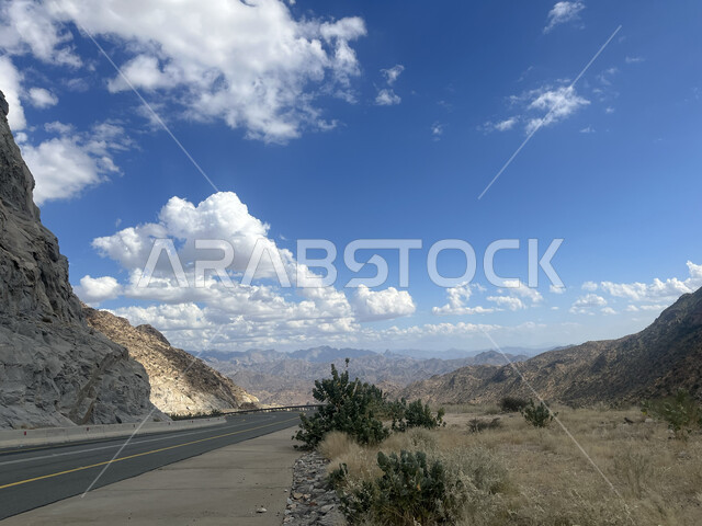 Mountainous terrain and heights, view of white clouds in the sky, natural formations and formations of rocks and stones, landmarks and tourist places in Saudi Arabia, the highway of the Shafa Mountains in the city of Taif in the Kingdom, paved paths and roads