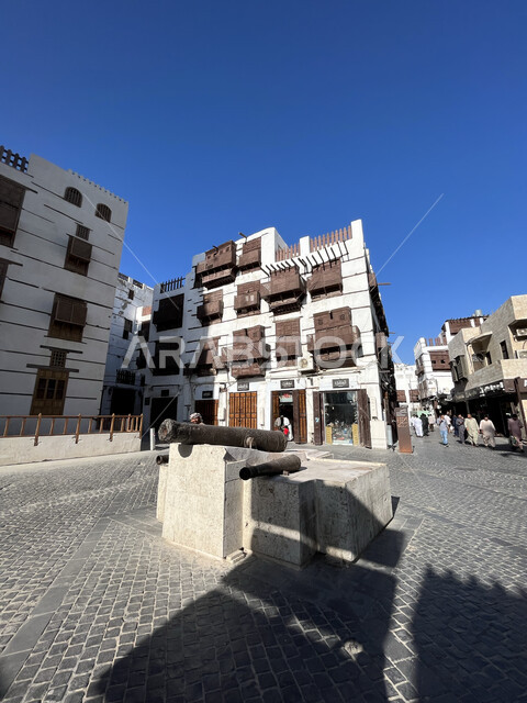 الفن الهندسي المعماري على الطراز العربي الإسلامي، النوافذ الخشبية والأبنية القديمة في وقت النهار، أماكن سياحية في المملكة، القرية التاريخية في مدينة جدة، الاهتمام بزراعة الأشجار الخضراء في السعودية