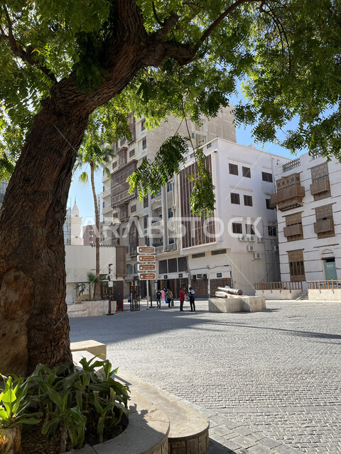 توافد الزوار إلى البلدة الاثرية، القرية التاريخية في مدينة جدة، الفن الهندسي المعماري على الطراز العربي الإسلامي، النوافذ الخشبية والأبنية القديمة في وقت النهار، أماكن سياحية جذابة في المملكة، الاهتمام بزراعة الأشجار الخضراء في السعودية