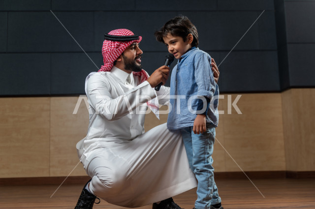 A Saudi Gulf man in one of the theatrical parties, honoring a student in front of the audience in the school theater, interaction with a young child who is one of the theater audiences, dialogues and discussions