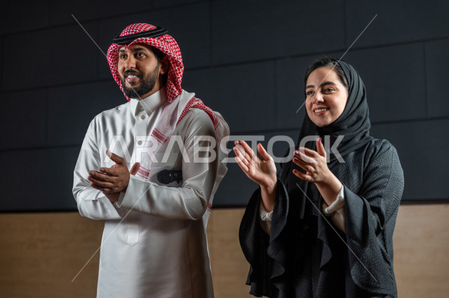 مرأه ورجل سعوديان خليجيان يقومان بالتقديم المسرحي على خشبة المسرح ، التفاعل مع الجمهور ، تحية الجماهير ،  تقديم العروضات المسرحية ، القاء الخطابات ، الحوارات و النقاشات ، اداء تمثيلي ، ايماءات وجه و يدين مختلفة ، الفن المسرحي