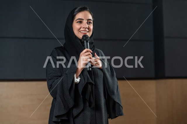 مرأه سعودية خليجية تقوم بالتقديم المسرحي على خشبة المسرح تتفاعل مع الجمهور ،  تقديم العروضات المسرحية ، القاء الخطابات ، الحوارات و النقاشات ، اداء تمثيلي ، ايماءات وجه و يدين مختلفة ، الفن المسرحي