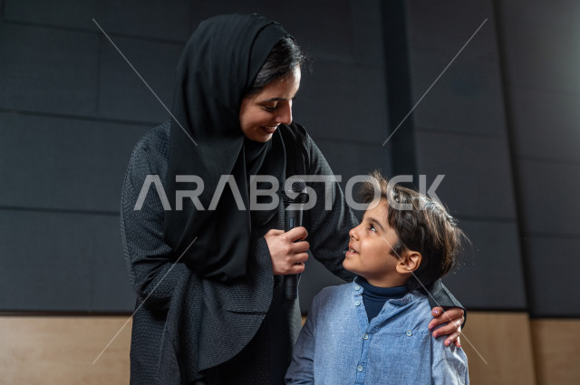A saudi teacher's photo shoot honors a student in front of the audience at the school theater, a young Gulf child speaking with his microphone in his hand, an educational theater  