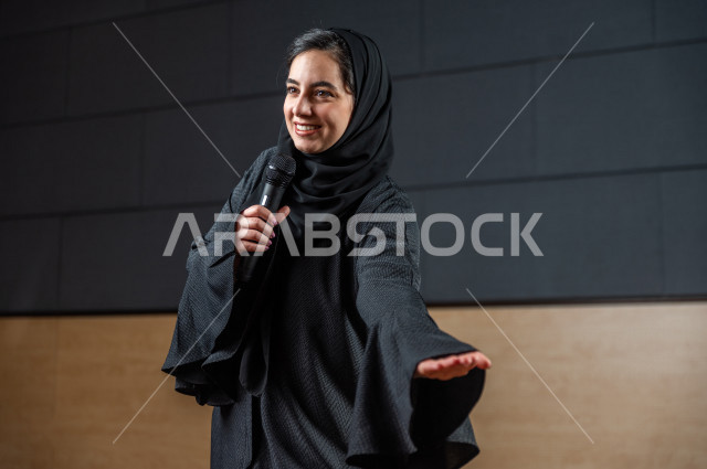 مرأه سعودية خليجية تقوم بالتقديم المسرحي على خشبة المسرح تتفاعل مع الجمهور ،  تقديم العروضات المسرحية ، القاء الخطابات ، الحوارات و النقاشات ، اداء تمثيلي ، ايماءات وجه و يدين مختلفة ، الفن المسرحي