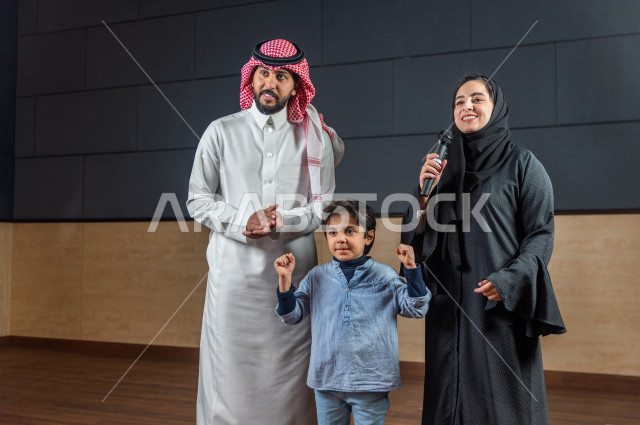  فتى سعودي خليجي في احدى الحفلات المسرحية ، يقف على خشبة المسرح مع والديه ، تشجيع الاهل للأبناء ، تكريم  الطالب المتفوق أمام الحضور في المسرح المدرسي ، اداء تمثيلي ، تحية الجماهير ،  تقديم العروضات المسرحية ، الحوارات و النقاشات