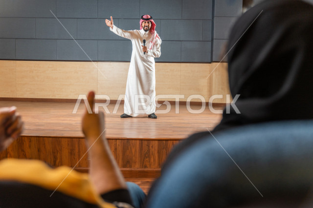 مقدم مسرحي سعودي خليجي على خشبة المسرح يتفاعل مع الجمهور ،  تقديم العروضات المسرحية ، القاء الخطابات ، الحوارات و النقاشات ، اداء تمثيلي ، ايماءات وجه و يدين مختلفة ، الفن المسرحي 