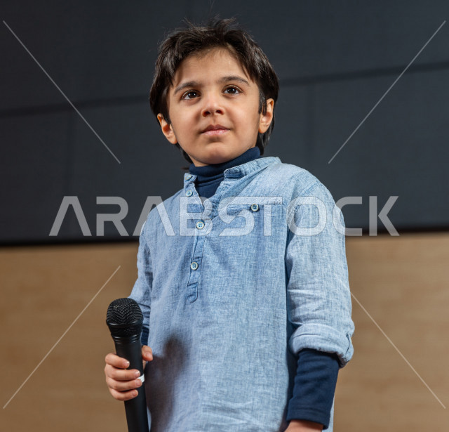 فتى سعودي خليجي في احدى الحفلات المسرحية ، يقف على خشبة المسرح و ينظر الى الجمهور، تكريم  الطالب المتفوق أمام الحضور في المسرح المدرسي  ، اداء تمثيلي ، تحية الجماهير ،  تقديم العروضات المسرحية