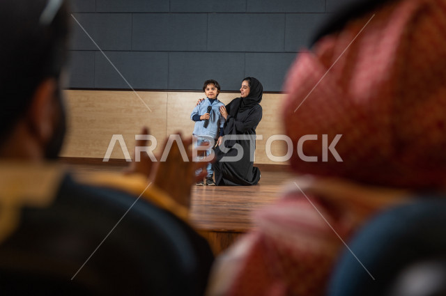 لقطة تصوير معلمة سعودية تكرم طالب أمام الحضور في المسرح المدرسي ,  طفل خليجي صغير يتحدث وبيده المايكرفون , مسرح تعليمي  