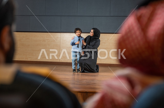 لقطة تصوير معلمة سعودية تكرم طالب أمام الحضور في المسرح المدرسي ,  طفل خليجي صغير يتحدث وبيده المايكرفون , مسرح تعليمي  