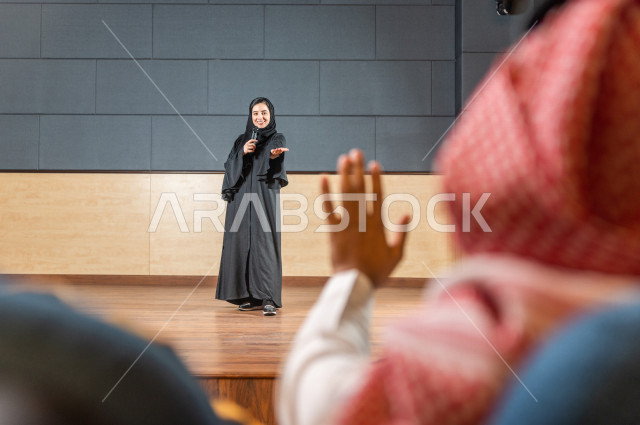 مرأه سعودية خليجية تقوم بالتقديم المسرحي على خشبة المسرح ، تتفاعل مع الجمهور ، تحية الجماهير ،  تقديم العروضات المسرحية ، القاء الخطابات ، الحوارات و النقاشات ، اداء تمثيلي ، ايماءات وجه و يدين مختلفة ، الفن المسرحي 