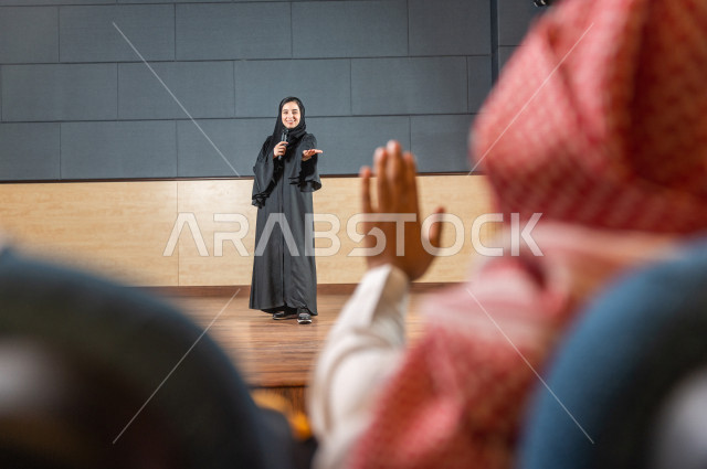 مرأه سعودية خليجية تقوم بالتقديم المسرحي على خشبة المسرح ، تتفاعل مع الجمهور ، تحية الجماهير ،  تقديم العروضات المسرحية ، القاء الخطابات ، الحوارات و النقاشات ، اداء تمثيلي ، ايماءات وجه و يدين مختلفة ، الفن المسرحي 
