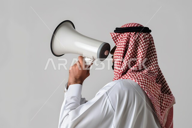 Calling, announcing and drawing attention, using the microphone to announce something, a close-up portrait of a Saudi Gulf Arab man wearing the traditional dress and shemagh, holding a white loudspeaker in his hand, white background.