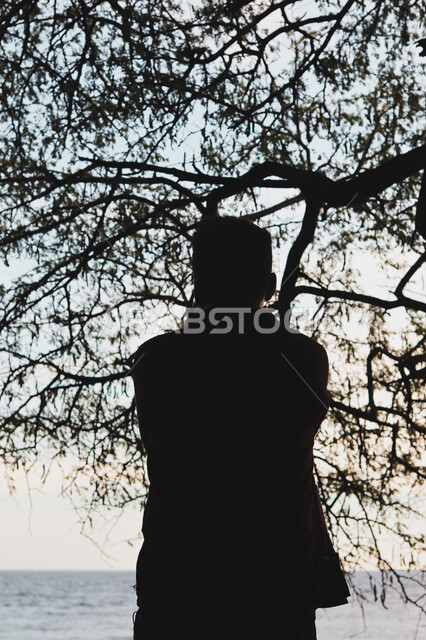  قضاء وقت ممتع بتأمل مناظر الطبيعة الهادئة، صورة ظلية من الخلف لشاب عربي خليجي سعودي يقف على الشاطئ الرملي، الاستمتاع بالنظر الى ساحل البحر، الواجهة البحرية والمناطق الطبيعية في المملكة العربية السعودية، النزهات والرحلات في فصل الصيف، سالوييت