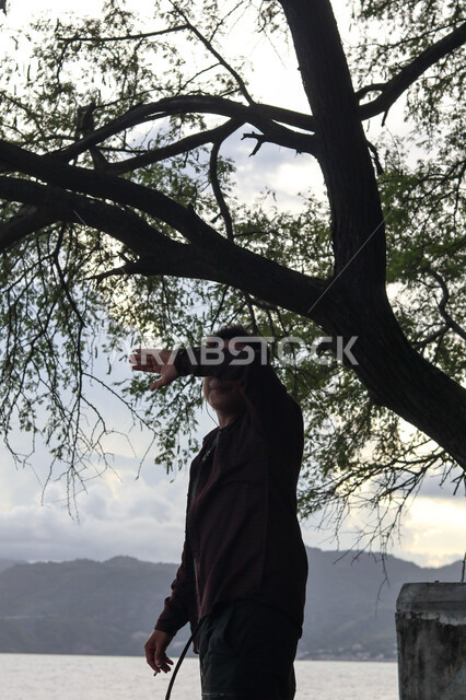  قضاء وقت ممتع بتأمل مناظر الطبيعة الهادئة، صورة ظلية من الخلف لشاب عربي خليجي سعودي يقف على الشاطئ الرملي، الاستمتاع بالنظر الى ساحل البحر، الواجهة البحرية والمناطق الطبيعية في المملكة العربية السعودية، النزهات والرحلات في فصل الصيف، سالوييت