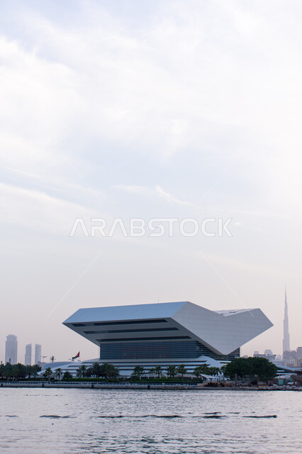 مراكز نشر الكتب والمطبوعات, تصميم المكتبة الفريد على شكل كتاب مفتوح, منارة ثقافية مشهورة في الامارات العربية المتحدة, خلفية ضبابية ببرج خليفة الشامخ، الموقع المتميز على ضفاف خور دبي لمكتبة محمد بن راشد آل مكتوم