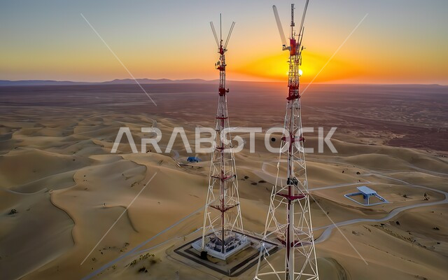 االتلال والكثبان الرملية في المملكة العربية السعودية، صورة من الاعلى لبرجي اتصالات في وسط الصحراء، الطبيعة الصحراوية والرمال الذهبية الناعمة وقت غروب الشمس