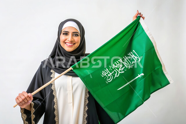 Celebrating national holidays and occasions, Flag Day March 11, Remembering Saudi National Day September 23, Raising the banner of monotheism and Islam, Close-up portrait of a veiled Saudi Arabian Gulf woman holding the green Saudi flag, Pride and pride in belonging to the homeland, white background