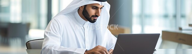 وظائف و مهن ادارية مكتبية, دمج التكنولوجيا مع الحياة العملية، إدارة شؤون الأعمال وتنظيمها عبر الاجهزة التقنية، صورة بانورامية لرجل اعمال عربي خليجي سعودي يرتدي الزي التقليدي يقوم بالعمل على الحاسوب المحمول داخل المكتب