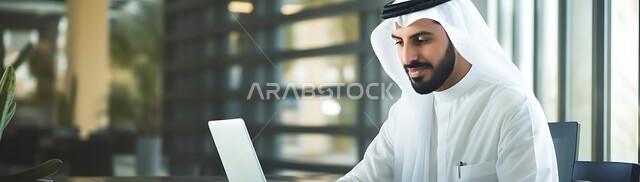 دمج التكنولوجيا مع الحياة العملية، مهن ووظائف ادارية مكتبية, إدارة شؤون الأعمال وتنظيمها عبر الاجهزة التقنية، صورة بانورامية لرجل اعمال عربي خليجي سعودي يرتدي الزي التقليدي يقوم بالعمل على الحاسوب المحمول داخل المكتب