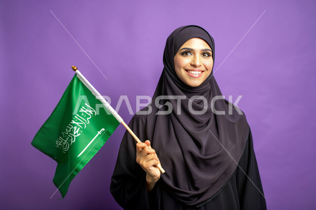 يوم العلم 11 مارس، الاحتفال بالأعياد والمناسبات الوطنية، استذكار اليوم الوطني السعودي 23 سبتمبر، رفع راية التوحيد والإسلام، بورتريه مقرب لامرأة عربية خليجية سعودية محجبة تحمل بيدها علم السعودية الاخضر، الفخر و الاعتزاز بالانتماء للوطن، خلفية ارجوانية