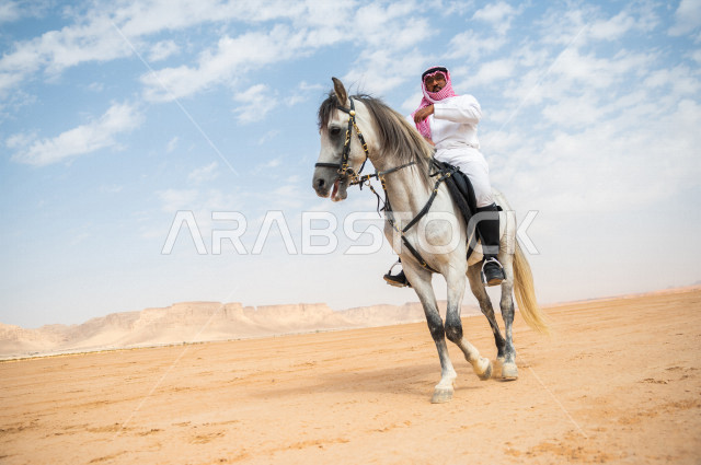 فارس سعودي خليجي يمتطي الخيل في الصحراء السعودية  الخلابة في وضع النهار، مدرب الخيول، الخيل العربي الأصيل، هواية ركوب الخيل ، الفروسية ، انشطة و فعاليات لركوب الخيل  ، مهارات و انشطة ترفيهية