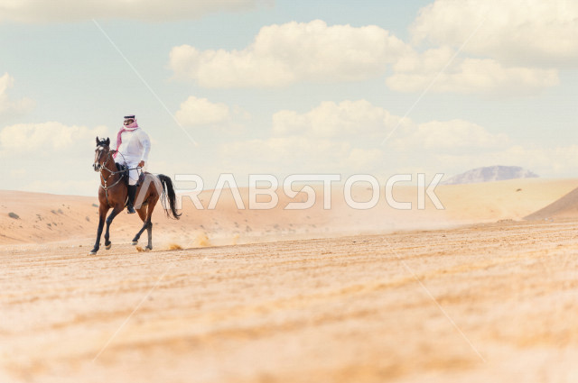 فارس سعودي خليجي يمتطي الخيل بسرعة عالية في الصحراء السعودية  الخلابة ، ترويض الخيل ، مدرب الخيول، الخيل العربي الأصيل، هواية ركوب الخيل ، الفروسية ،  مهارات و انشطة ترفيهية ، جمال الصحراء في المملكة العربية السعودية