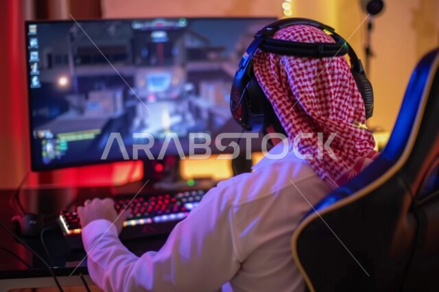 Integrating fun and entertainment with the virtual world, using modern and advanced devices and technologies, a picture from the back of a Saudi Gulf Arab young man wearing the traditional dress and shemagh sitting in front of the computer screen, a professional Saudi gamer in electronic video games, the online store for games and competitions
