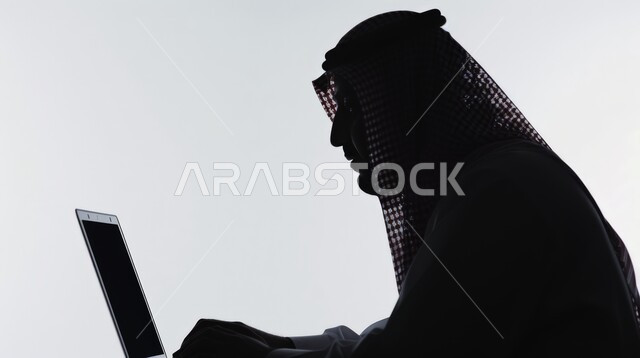 مفهوم البيع والشراء اونلاين، تصفح الإنترنت وإستخدام الاجهزة التقنية الحديثة, العمل عن بعد، بورتريه صورة ظلية لرجل عربي خليجي سعودي يجلس على مكتب أمام الحاسوب المحمول، التسويق الإلكتروني عبر الانترنت، خلفية بيضاء