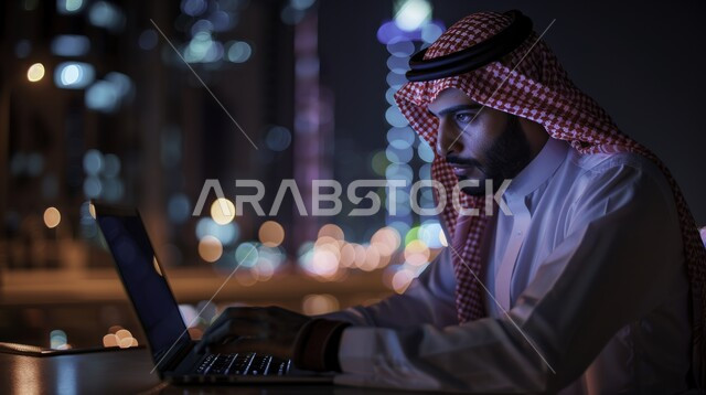 إيماءات الاندماج والتركيز، مهن ووظائف ادارية مكتبية, دمج التكنولوجيا مع الحياة العملية، إدارة شؤون الأعمال وتنظيمها عبر الاجهزة التقنية، رجل اعمال عربي خليجي سعودي يرتدي الزي التقليدي يقوم بالعمل على الحاسوب المحمول داخل مكتب، خلفية الأبراج المضيئة وقت الليل