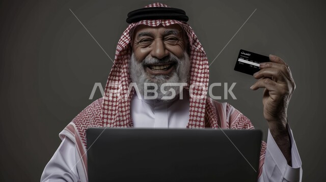 امكانية تسديد الفواتير عن بعد، الشراء والدفع عبر برامج و تطبيقات التابليت، ايماءات وجه ويدين تدل على الدهشه والاعجاب، بورتريه لرجل مسن عربي خليجي سعودي يرتدي الزي التقليدي يستخدم بطاقة الإئتمان البنكيه في التسوق الالكتروني، خلفية رمادية