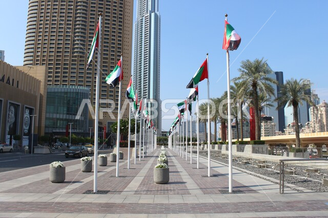 The flags of the UAE flying in the national sky, urban growth and development in buildings, towers and high skyscrapers, national holidays and events, celebration of the National Independence Day of the United Arab Emirates, pride in Emirati symbols and culture