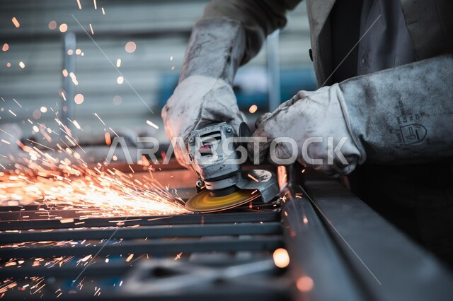 مهارة إتقان العمل في مصنع الحدادة, إعمار السعودية بسواعد أبنائها المعطاءة, أعمال ومشاريع البناء في المملكة, صورة مقربة ليدي عامل عربي خليجي سعودي يقوم بقص الحديد بوساطة المنشار الكهربائي, تطاير الشرر عند قص الفولاذ