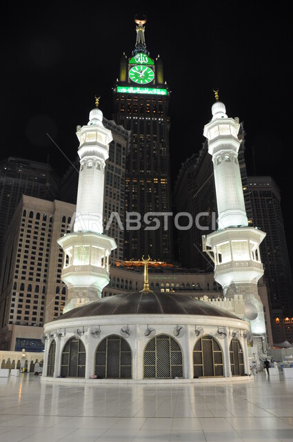  مبنى برج الساعة الملكي في مكة المكرمة ، معالم واماكن لأداء العبادات والتقرب الى الله تعالى، معالم دينية اسلامية مقدسة في المملكة العربية السعودية، الفن الهندسي المعماري لبناء الابراج وناطحات السحاب، صورة مقربة لمبنى امام برج الساعة الملكي في مكة المكرمة ليلا.