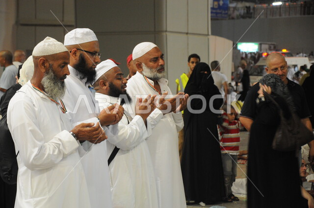 وقوف المعتمرين والحجاج رافعين ايديهم ، العبادة والتقرب إلى الله في معالم واماكن اسلامية دينية مقدسة, حجاج بيت الله الحرام يرتدون لباس الإحرام  في مكة المكرمة في المملكة العربيه السعودية ، لاداء مناسك الحج والعمرة.