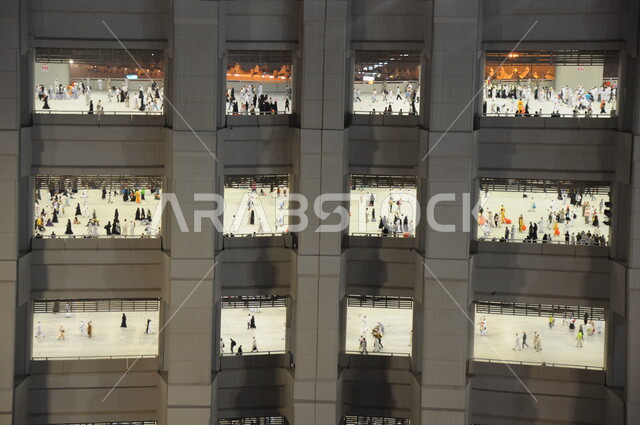 Floors in the Sacred House where pilgrims walk, worshiping and getting closer to God in sacred Islamic religious landmarks and places. Pilgrims of the Sacred House of God wear the Ihram dress in Mecca in the Kingdom of Saudi Arabia, to perform the rituals of Hajj and Umrah.