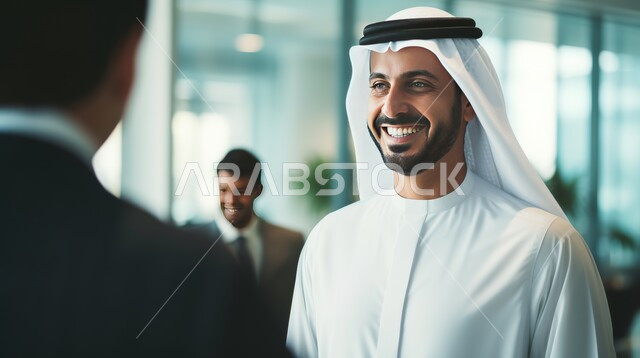 تبادل أطراف الحديث مع الزملاء، إيماءات البهجة والسرور، مهن ووظائف إدارية، بيئة عمل مريحة في الشركات الإماراتية، رجل عربي خليجي إماراتي مبتسم يقف مع أحد الموظفين في مقر العمل