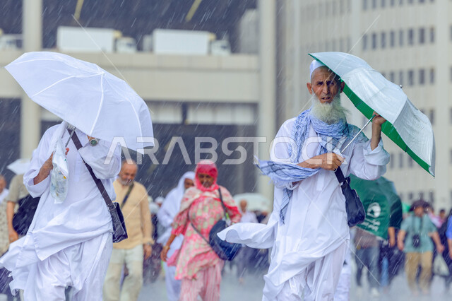 تأدية الفرائض الدينية الإسلامية , حجاج مسلمين يحملون شمسية يقومون بأداء مناسك الحج والعمرة , زيارة بيت الله الحرام في مكة المكرمة , العبادة و التقرب إلى الله , أجواء شتوية في المملكة العربية السعودية