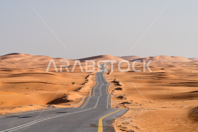 The formation of sand dunes and hills, an asphalt road extending along the desert, urban growth and development in the deserts of the Kingdom, a paved street for the passage of cars and accelerating the movement of passengers, the dry desert environment in Saudi Arabia, facilitating movement between wilderness areas and cities.