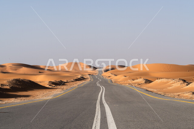 طريق اسفلتي ممتد على طول الصحراء, تشكل الكثبان والتلال الرملية, النمو والتطور العمراني في صحاري المملكة, شارع معبد لمرور السيارات وتسريع حركة المسافرين, البيئة الصحراوية الجافة في السعودية, تسهيل التنقلات بين المناطق البرية والمدن