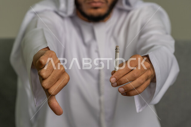 التوقف عن اتباع العادات السلوكية الضارة وتعاطي المواد السامة، صورة مقربة لأيدي شاب عربي خليجي إماراتي يحارب عادة التدخين، ايماءات تدل على الحذر من ادمان السجائر، تعابير الرفض وعدم الرضا، المعاناة من الاضطرابات النفسية والمشاكل الصحية