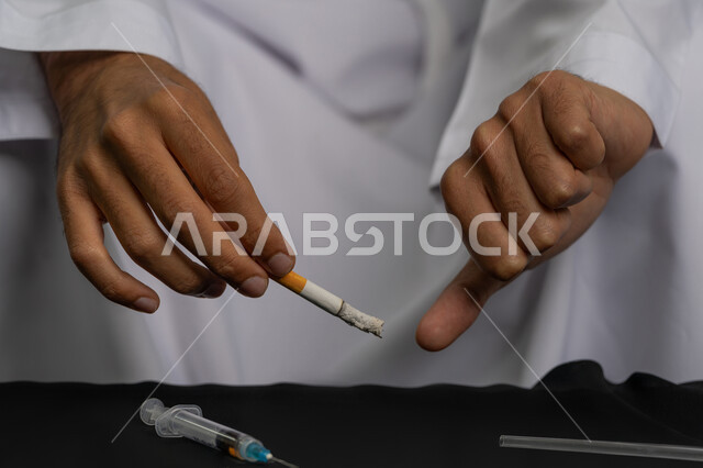 التوقف عن اتباع العادات السلوكية الضارة وتعاطي المواد السامة، صورة مقربة لأيدي شاب عربي خليجي إماراتي يقوم بمحاربة عادة التدخين، ايماءات تدل على الحذر من ادمان السجائر، تعابير الرفض وعدم الرضا، المعاناة من الاضطرابات النفسية والمشاكل الصحية
