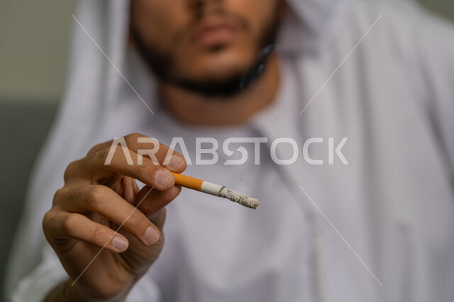 تعابير الرفض وعدم الرضا، المعاناة من الاضطرابات النفسية والمشاكل الصحية، ايماءات تدل على الحذر من ادمان السجائر، التوقف عن اتباع العادات السلوكية الضارة، صورة مقربة لشاب عربي خليجي إماراتي يقوم بمحاربة عادة التدخين