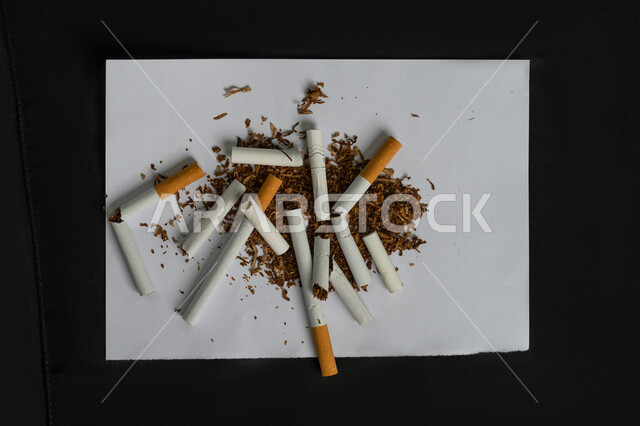 التحذير من الإدمان، محاربة عادة التدخين، التوقف عن اتباع العادات السلوكية الضارة وتعاطي المواد السامة، بورتريه مقرب لمجموعة من السجائر المتلفة على ورقة بيضاء، خلفية سوداء